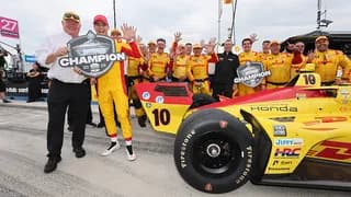 Chip Ganassi and Alex Palou celebrating with a 2026 champion sign with Palou holding up five fingers signaling his fifth championship.