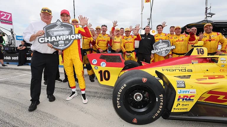 Chip Ganassi and Alex Palou celebrating with a 2026 champion sign with Palou holding up five fingers signaling his fifth championship.